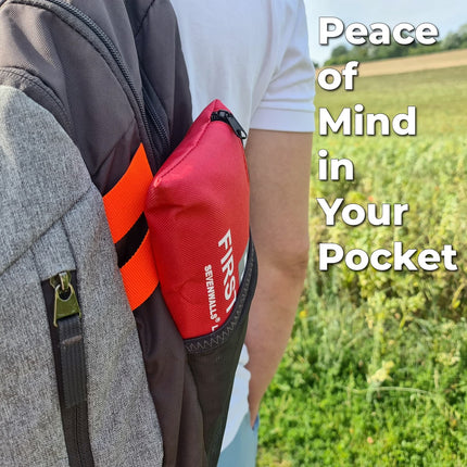 Red first aid kit attached to a backpack with text 'Peace of Mind in Your Pocket' in a natural setting.