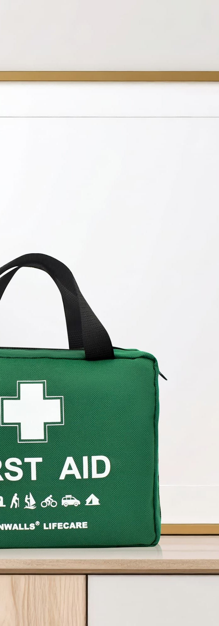 Green first aid kit on a wooden surface with decorative items and a framed picture in the background.