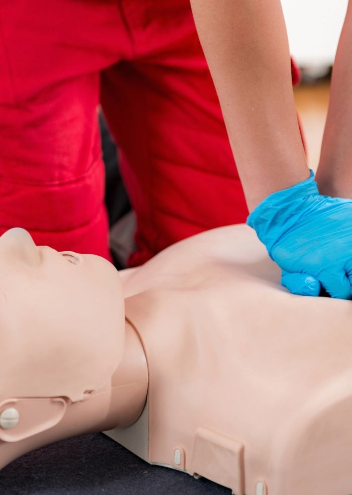 Person performing CPR on a mannequin with blue gloves