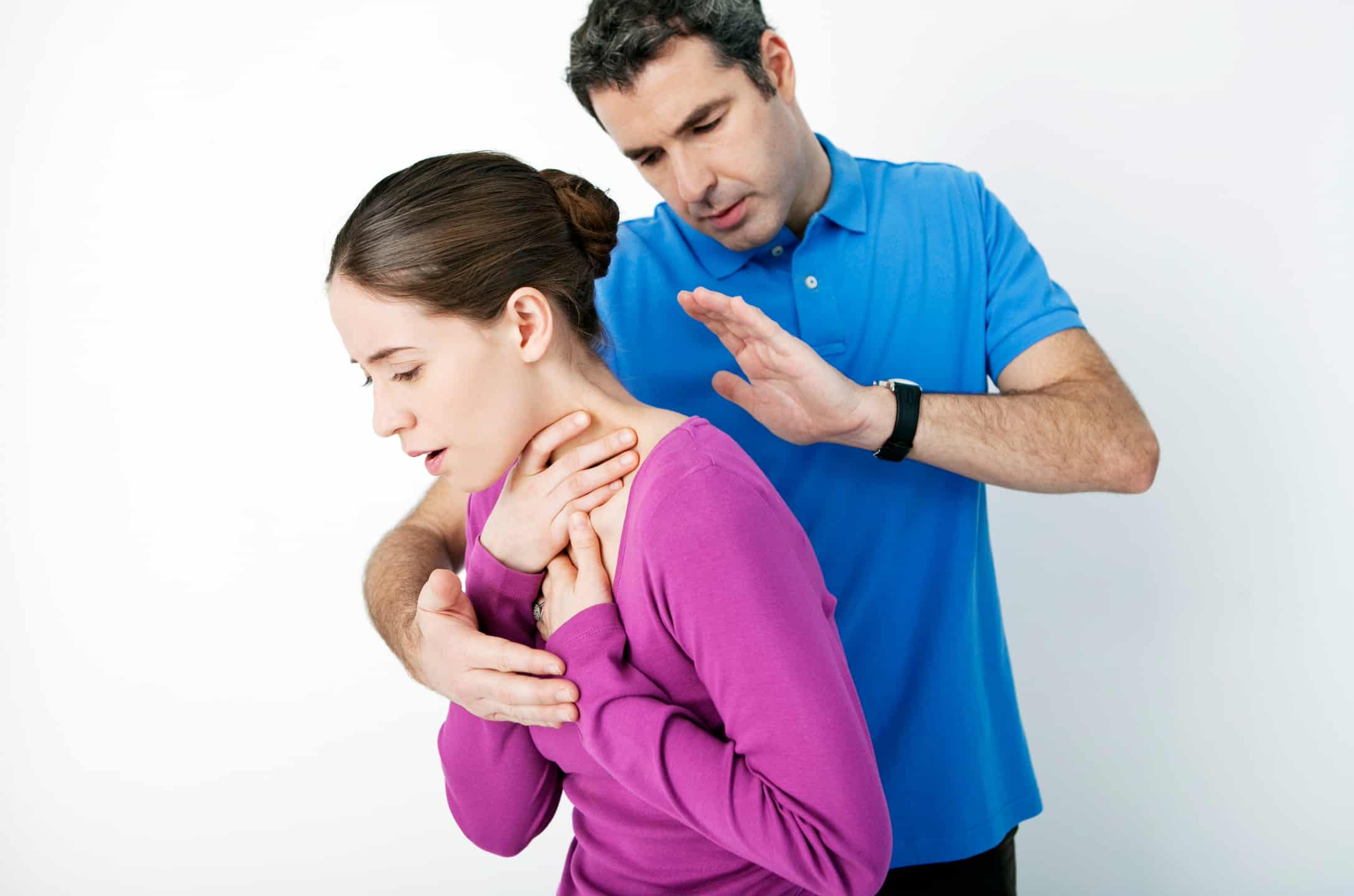 Person showing signs of choking by holding their throat, used in a general first aid choking guide.