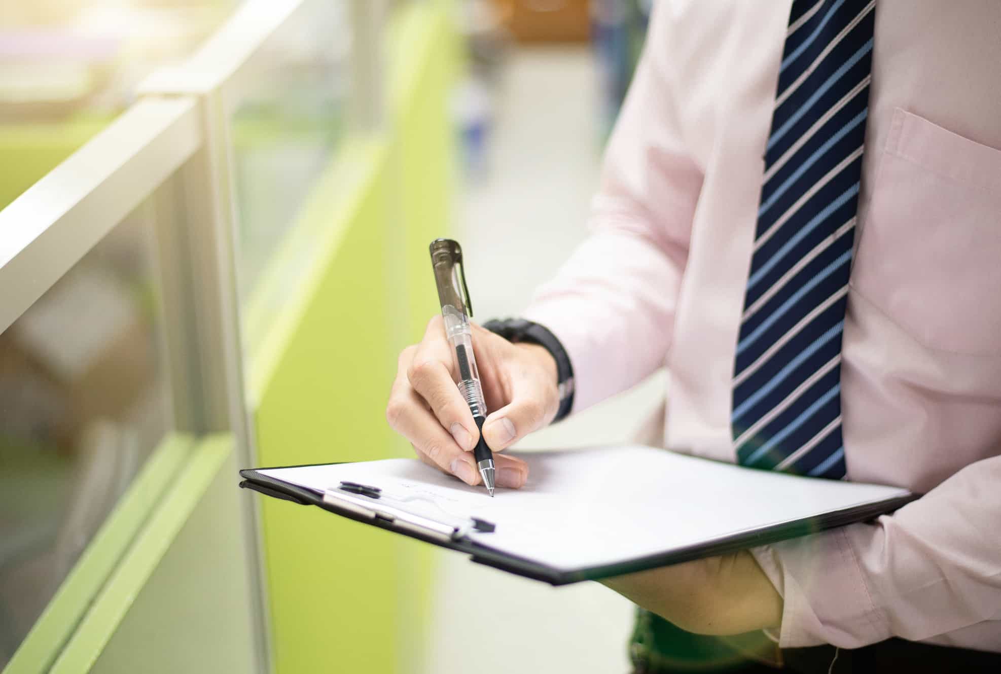 HSE inspector reviewing workplace first aid kit and safety documents in a UK office.