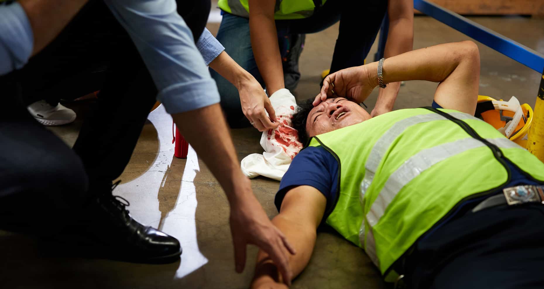 Workplace first aider assisting an injured visitor while an accident report is being completed.