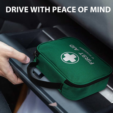 Green first aid kit with a cross symbol, held by a hand inside a car.