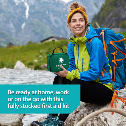 Person with a backpack holding a first aid kit in a mountainous area