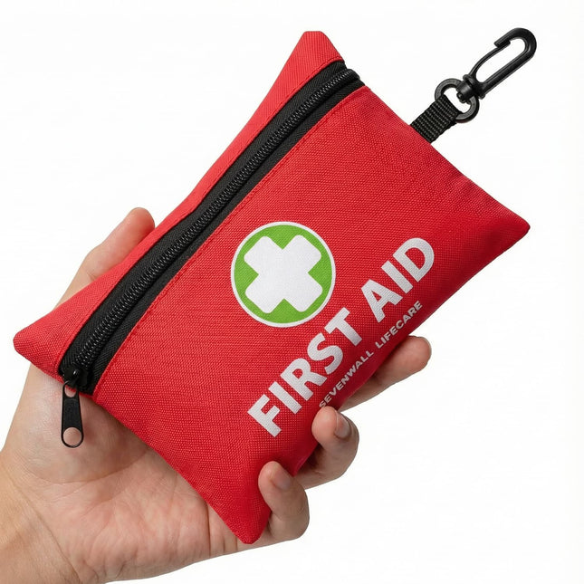 Red first aid kit with a green cross symbol held in a hand on a white background