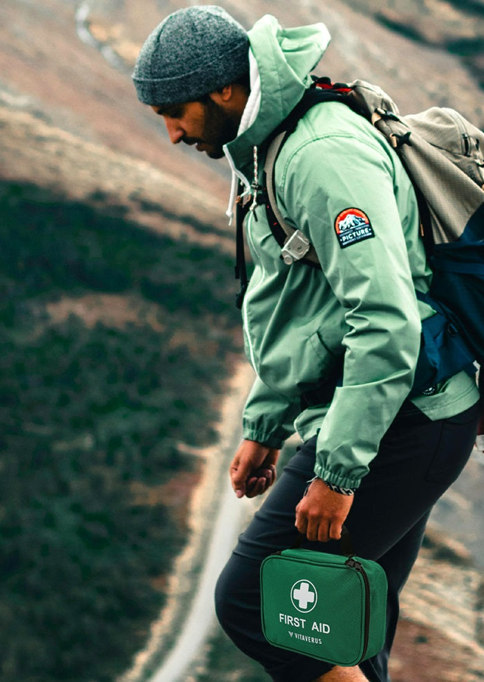 Person hiking with a backpack and first aid kit on a mountain path