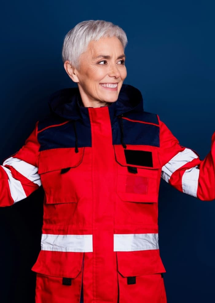 Person wearing a red safety suit with reflective stripes against a dark background